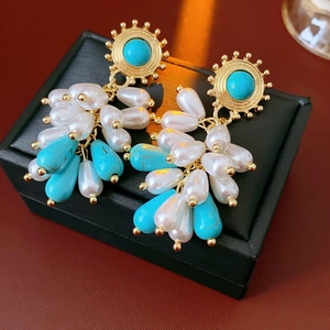 Close-up of vintage bohemian earrings with turquoise stones and dangling teardrop pearls