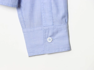 Close-up of light blue shirt cuff showing fabric texture and single white button