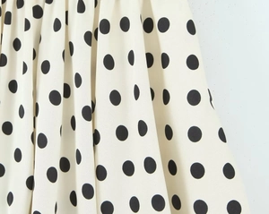 Detailaufnahme von weichem Chiffonstoff mit schwarzen Punkten auf cremefarbenem Hintergrund