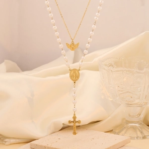 Double-layer gold necklace with pearls and Virgin Mary cross charms on silk background