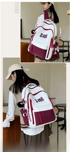 Detail of college-style backpack featuring burgundy accents and plush monster charm