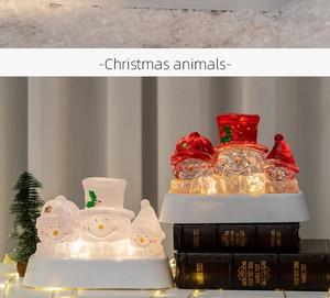 Close-up of warm glowing snowman figurines with red scarves on a festive table
