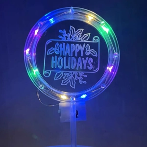 Macro shot of circular acrylic LED cake topper with colorful glowing lights and engraving
