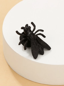 Detail of a black cicada brooch with textured wings on a white cylindrical stand