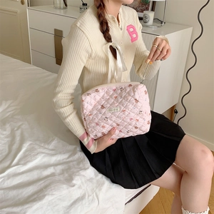 Trousse de toilette Snoopy matelassée rose tenue par un modèle dans une chambre
