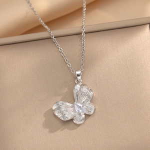 Collier pendentif papillon brossé avec zircons blancs sur un fond en satin champagne