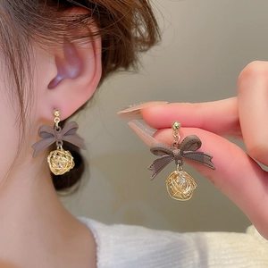 Detail of vintage bow earrings with gold mesh spheres shown on model and hand