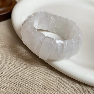 Macro detail of translucent white resin bracelet segments with stone texture on ceramic plate
