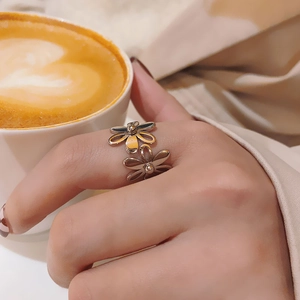 Close-up of a double flower titanium steel ring in gold finish on a hand