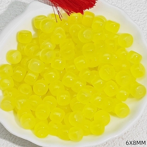Detailed view of yellow 6x8mm barrel beads with jade-like texture in a petal bowl