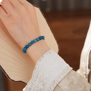 Close-up of blue apatite crystal beaded bracelet on wrist with fan background