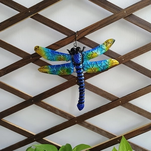 Close-up of blue and yellow gradient wings on a metal dragonfly wall decor piece