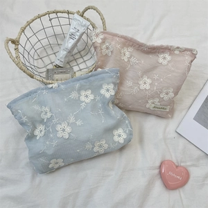 Detailed close-up of light blue and pink floral lace embroidery cosmetic storage bags