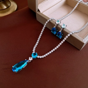 Detailansicht eines silbernen Schmucksets mit tropfenförmigen blauen Kristallanhängern