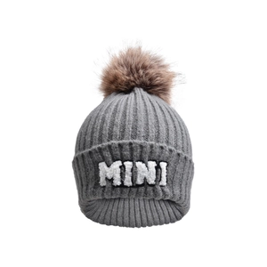 Detailed view of grey knitted beanie with MINI embroidery and a fluffy faux fur pompom