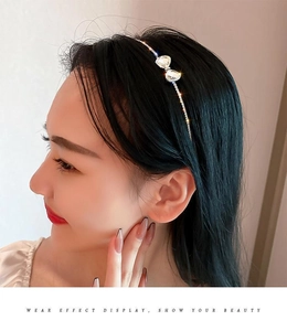 Close-up of a slim silver rhinestone bow headband worn by a model in a side view