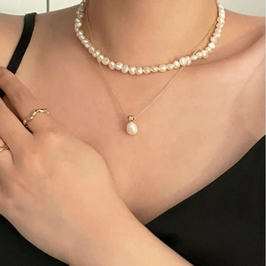 Close-up of double-layer baroque pearl necklace set with gold accents on model neck