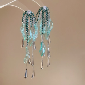 Detail view of long tassel earrings with green rhinestones and blue resin leaves
