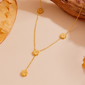 Détail d'un collier trèfle doré avec pendentifs brossés sur une surface en cuir beige