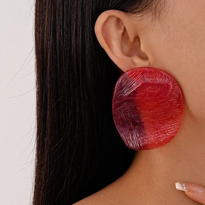 Detail shot of red resin earrings with irregular textured surface and translucent finish