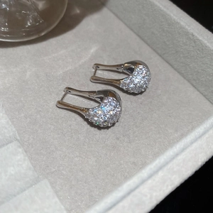 Détail de boucles d'oreilles argentées en zircon en forme de U dans un écrin de velours