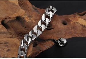 Vue détaillée du bracelet gourmette en acier titane argenté poli sur fond de bois flotté