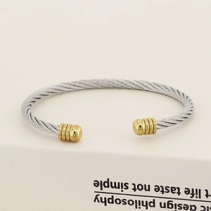 Detail of twisted cable steel bracelet with silver texture and golden ball ends