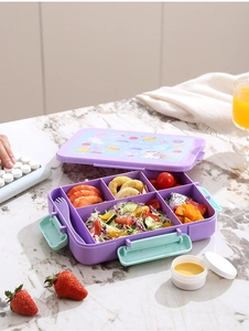 Close-up of a multi-compartment purple bento box with space pattern on marble table