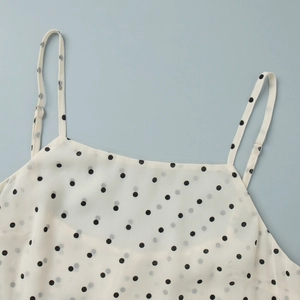 Detailed close-up of white polka dot camisole featuring thin straps and flat neckline