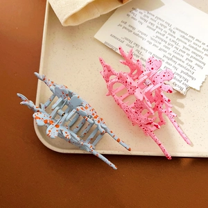 Pink and blue large conch-shaped hair claws with spot patterns on a display tray