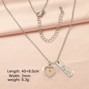 Macro detail of faith engraved pendant and mustard seed heart on silver necklace
