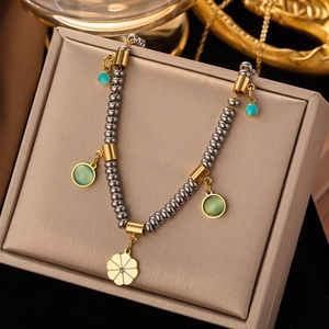 Macro detail of titanium necklace with gold and silver beads and a floral charm