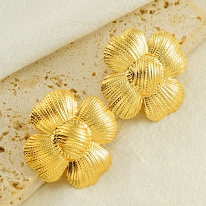 Macro detail of golden sunflower stud earrings featuring radial textures on stone tray