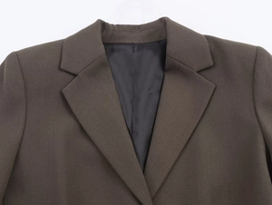 Close-up detail of dark brown twill fabric texture on a women's suit blazer collar