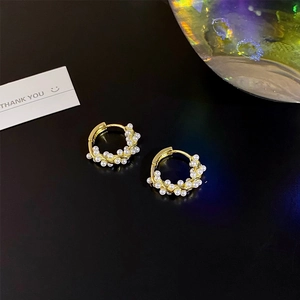 Detail of gold pearl hoop earrings with wrapped white pearls in French retro style