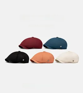 Detail showing five assorted colors of British style newsboy caps with metallic side buttons