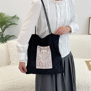 Detail of black canvas tote with pink floral embroidery and textured fabric finish