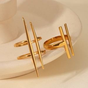 Detailed view of two gold geometric stainless steel rings on a beige ceramic plate