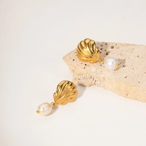Détail macro des boucles d'oreilles coquillage dorées avec perles d'eau douce élégantes