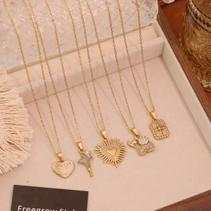 Detail of gold-plated necklaces with heart, elephant, and star pendants on velvet tray
