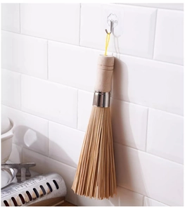 Bamboo dish brush with wooden handle hanging on white tile wall in a modern kitchen