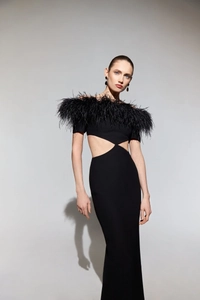Detail of elegant black off-shoulder dress featuring premium feather trim and waist cutout