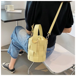 Detail of yellow woven bucket bag featuring premium leather texture and crossbody strap