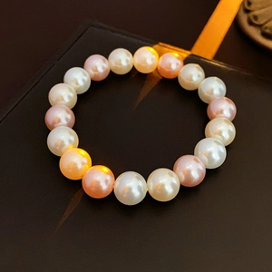 Detailed macro view of high-luster white, pink, and orange pearl bracelet on dark background