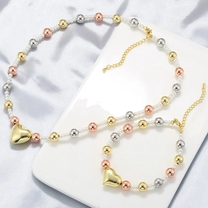 Detail view of tri-color bead necklace and bracelet set with golden heart pendant