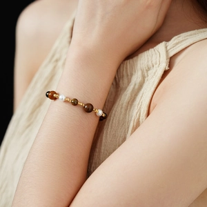Close-up of beaded bracelet with tiger eye stones, white pearls and gold hollow beads