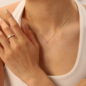 Close-up of gold-plated necklace with pink gemstone pendant and matching ring on model