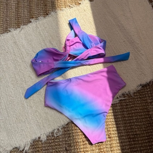 Bikini dégradé bleu et violet avec haut torsadé et culotte haute posés sur un tapis