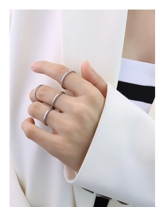 Set of four minimalist silver stainless steel rings on hand with a professional white blazer