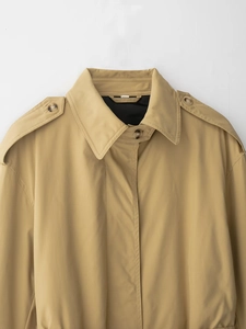Détail du col d'un trench-coat kaki avec épaulettes et boutons effet marbre